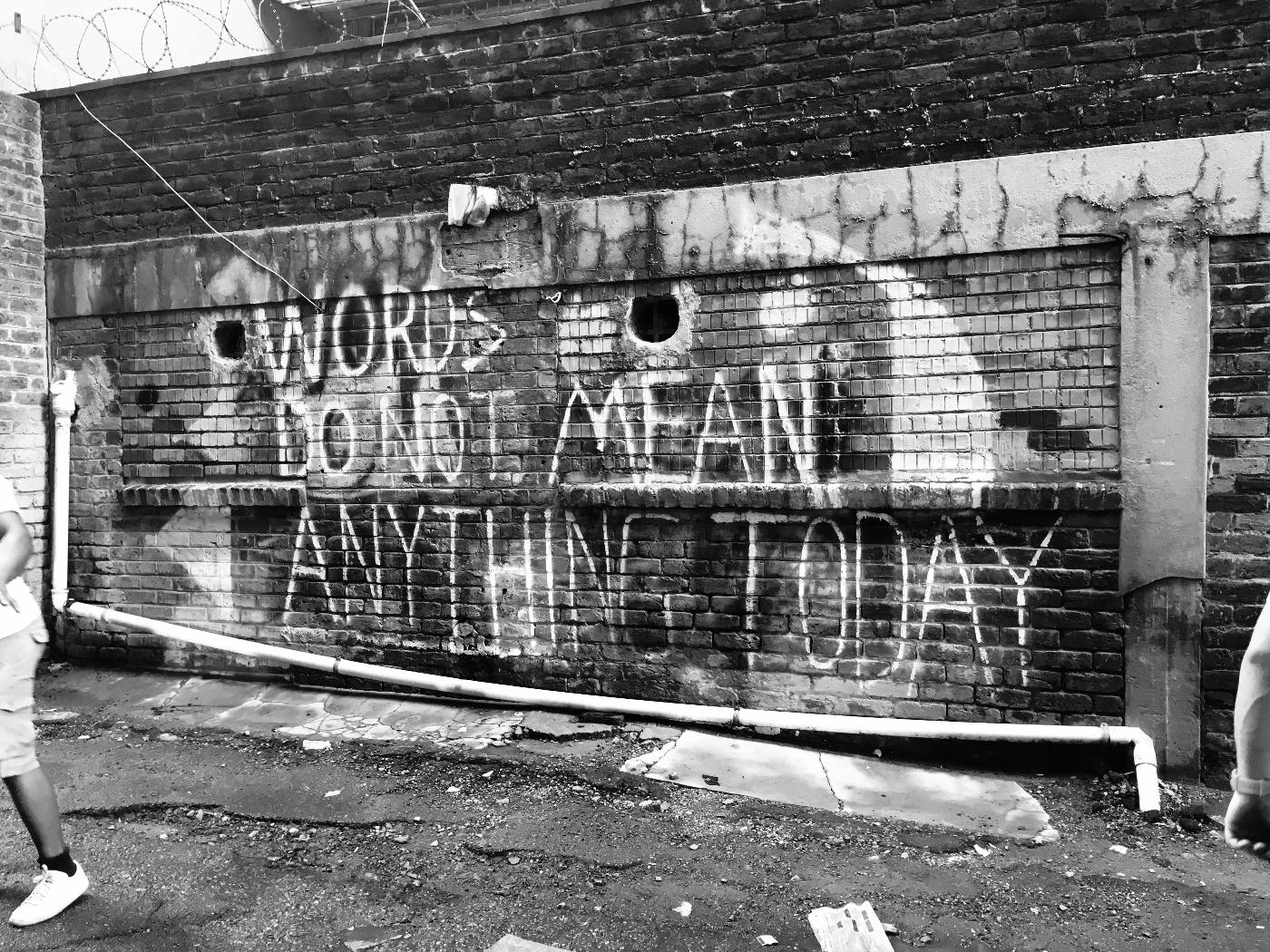 a decrepit wall with Words Do Not mean Anything Today written on it.