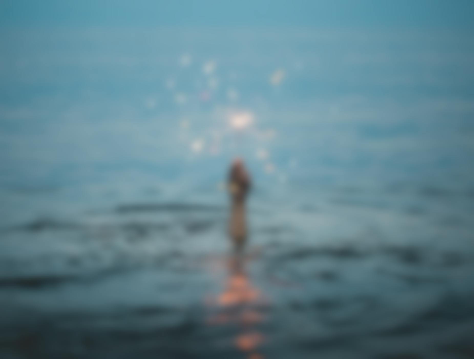 A hand holding a sparkler rising above water