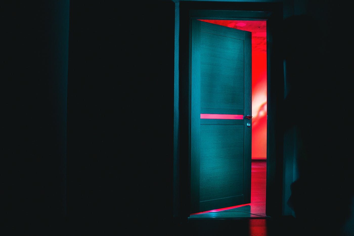 a dark hallway and a door opening into red
