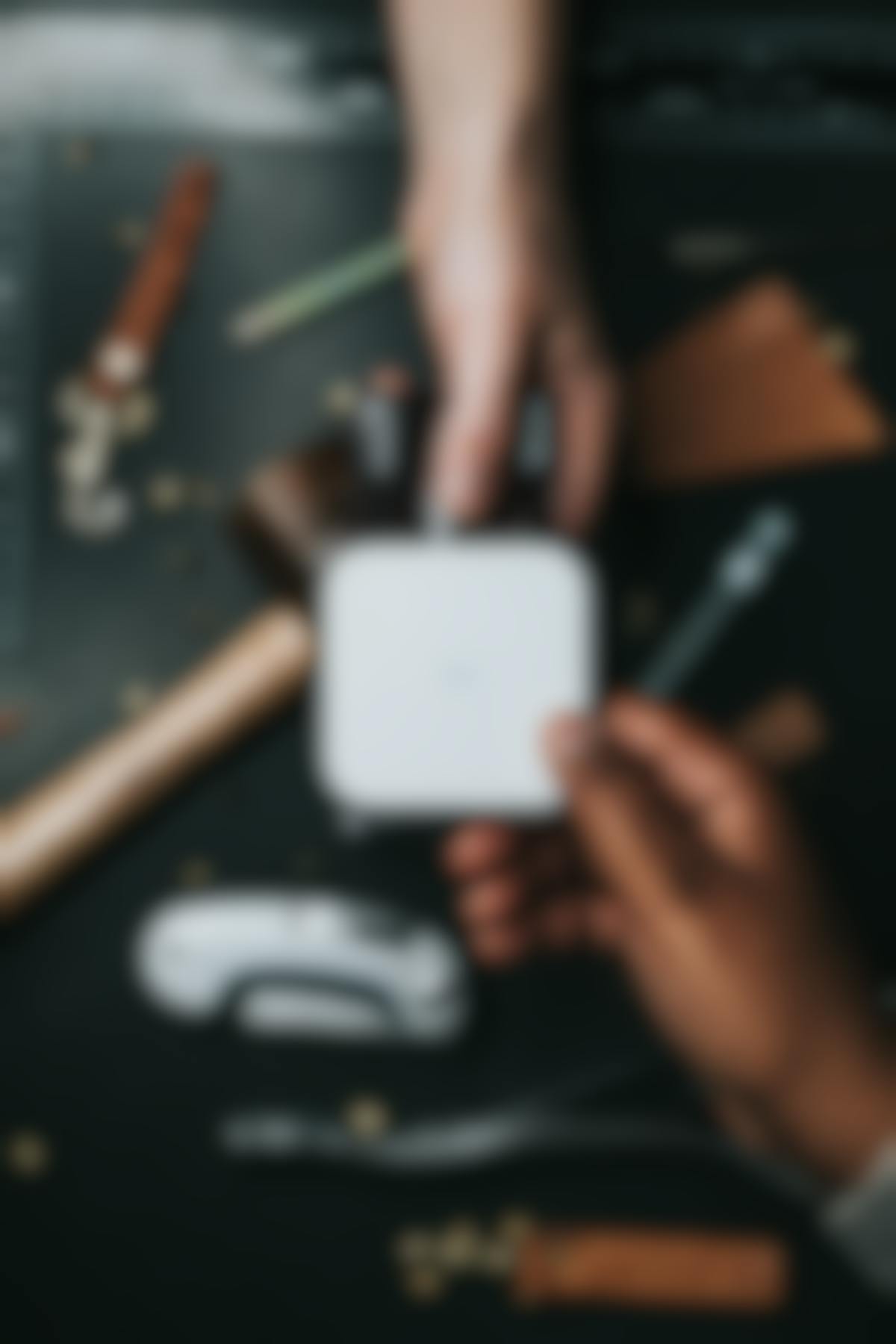 Two hands operating a debit card machine over a table of tools.