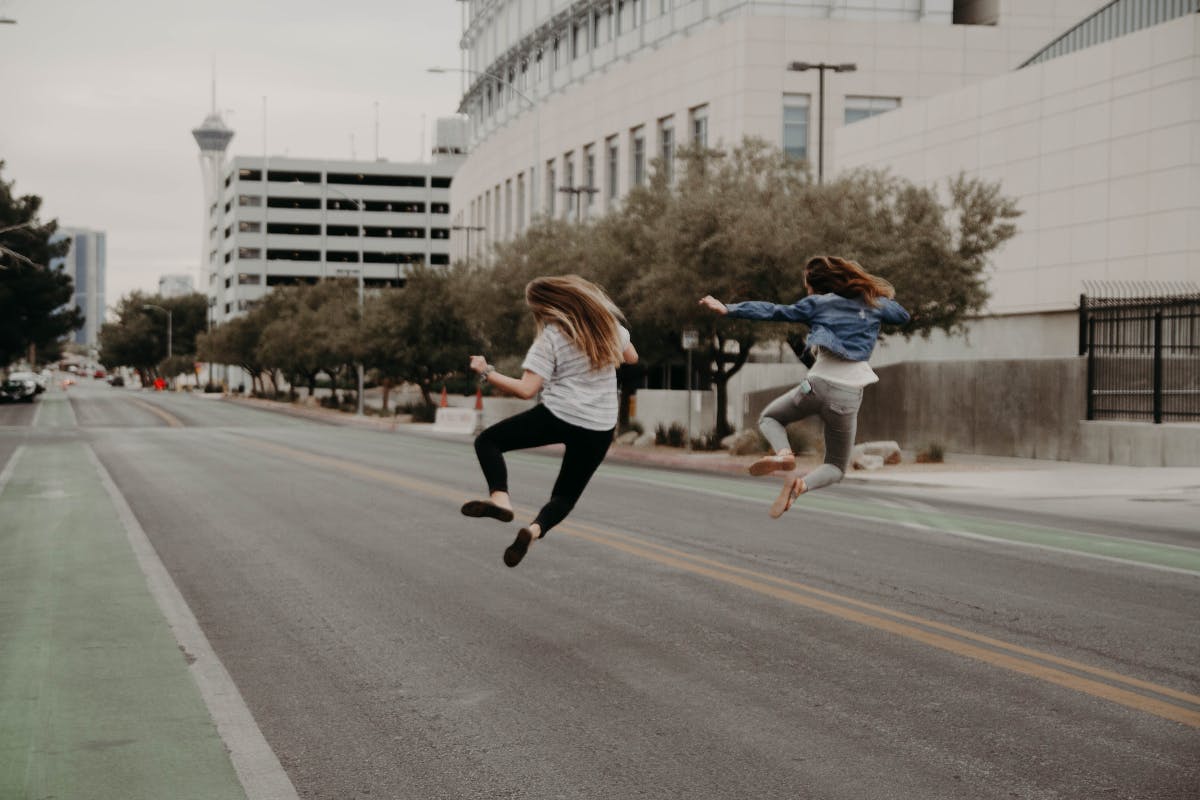two women on an empty street kicking up their heels