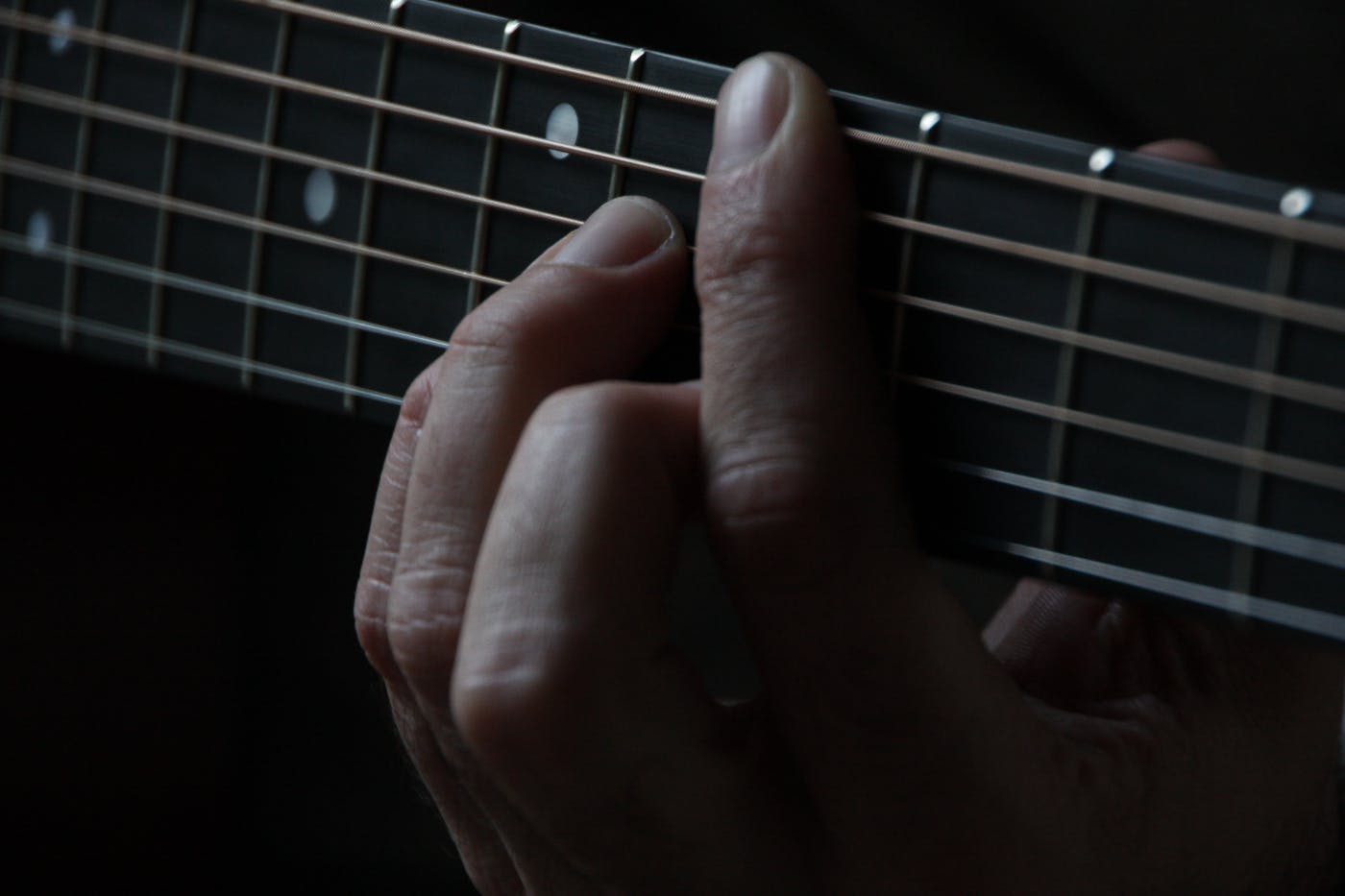 A hand fretting a guitar