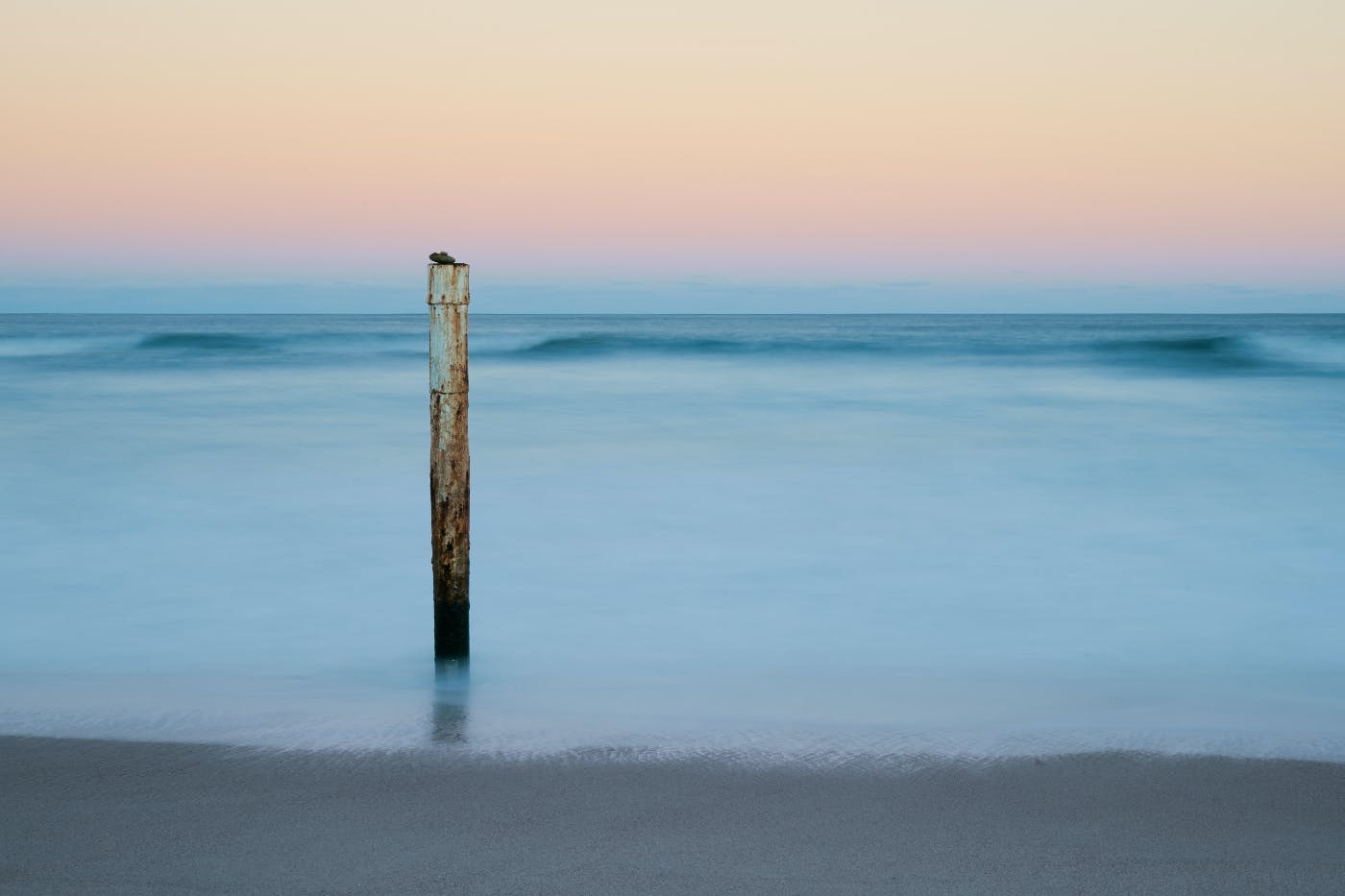 A post with a rock on it sticking out of the water