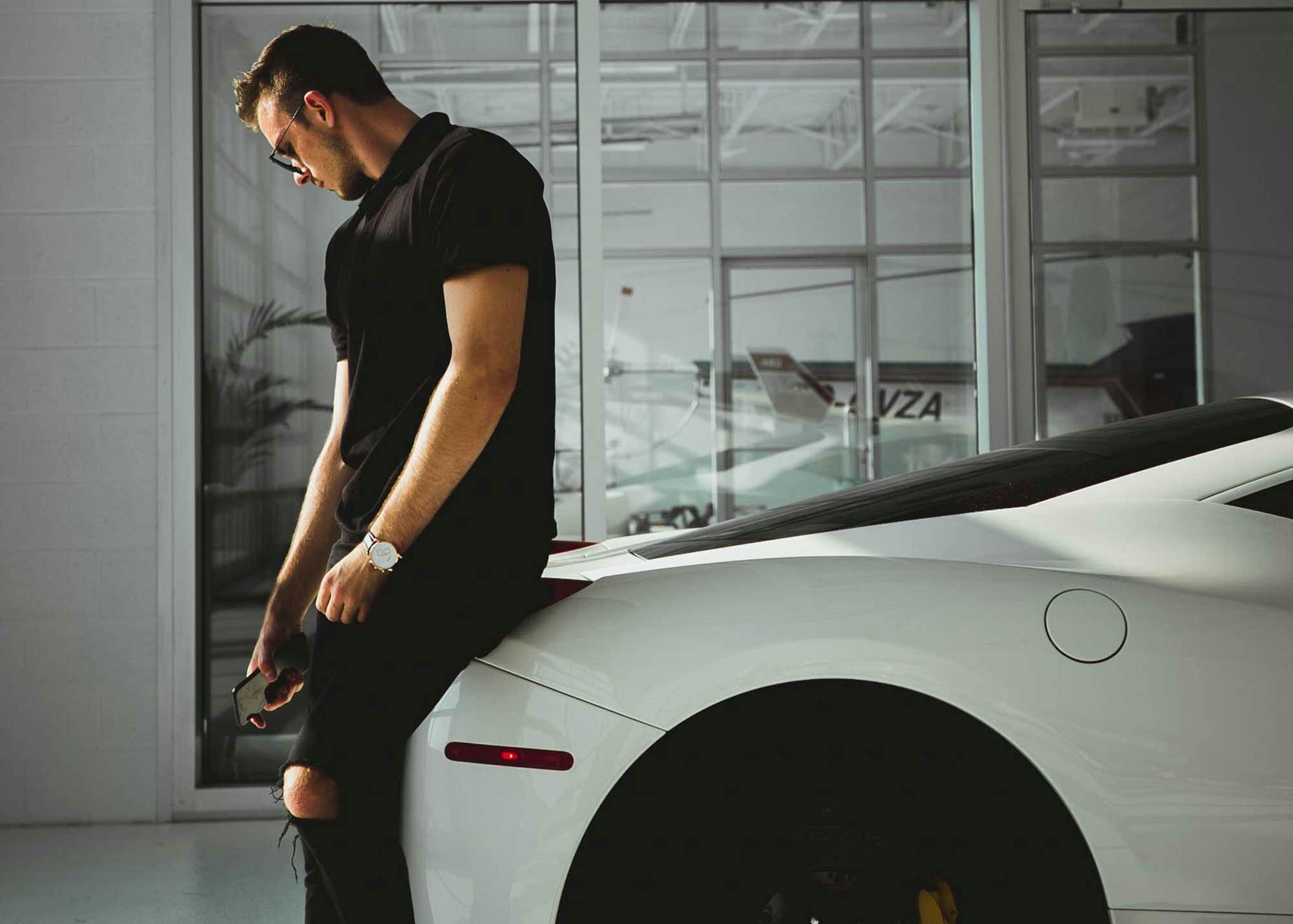 Man leaning against his luxury car