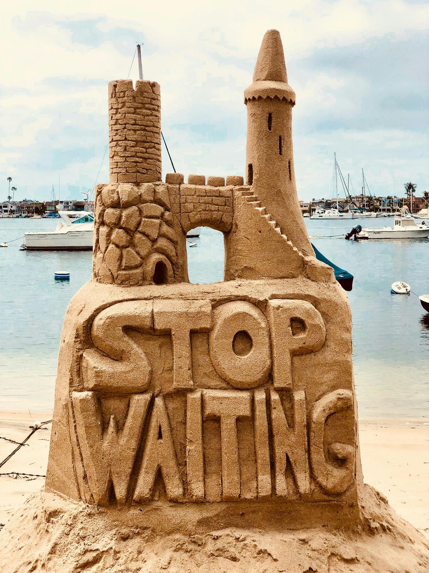 A sand castle with Stop Waiting on the side wall