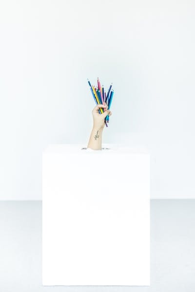 hand coming out of box holding pencils