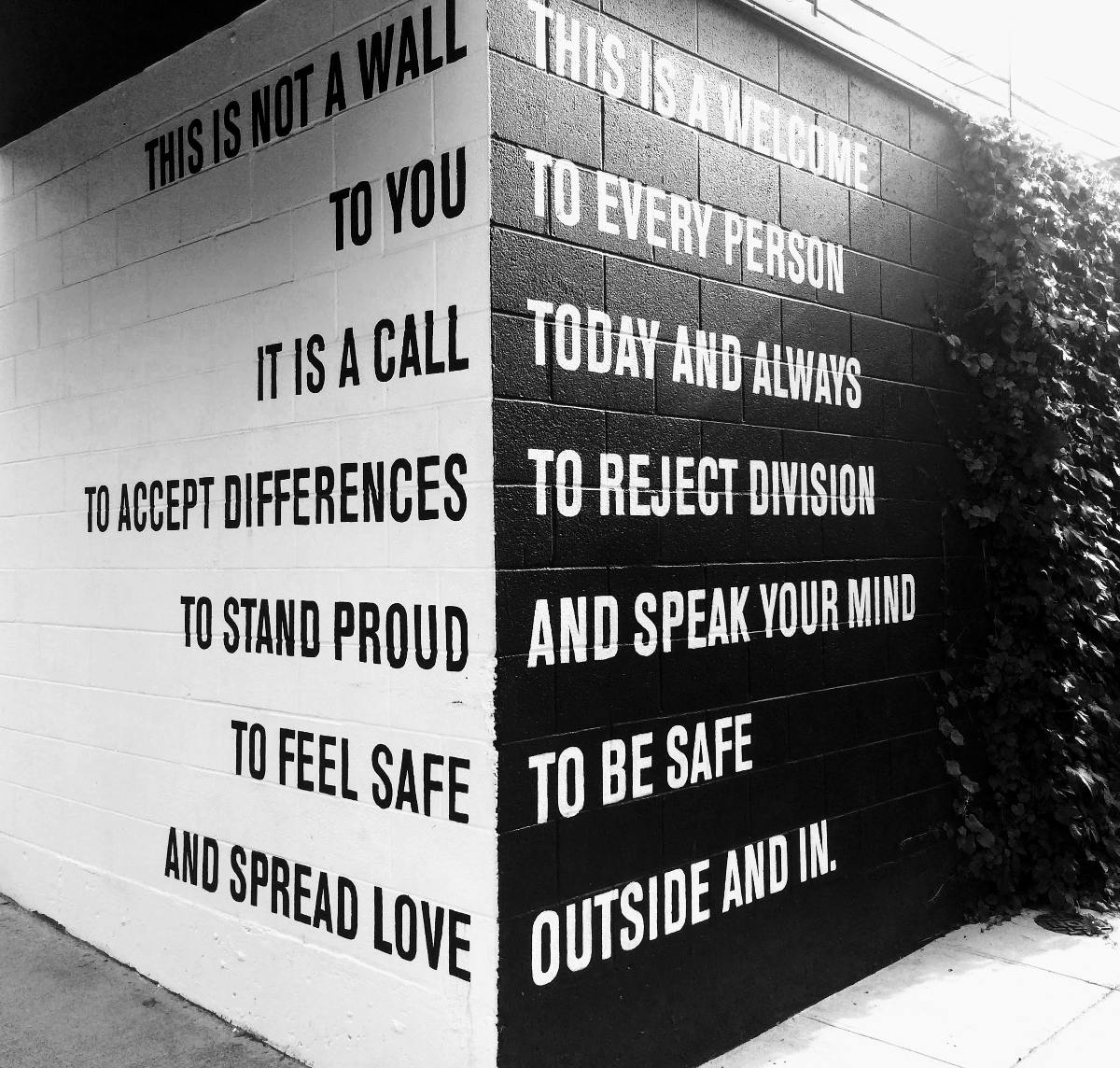 a corner of a two walls, left in white right in black with positive words written on it