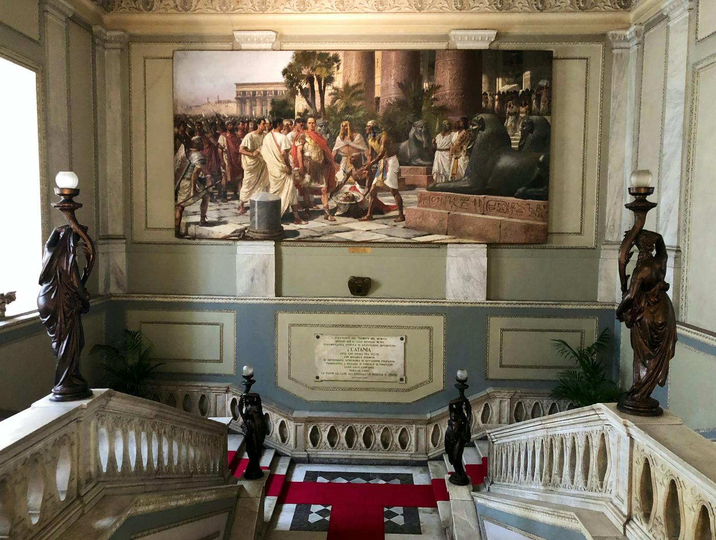 A stairway in a museum with a large painting of Christ bound