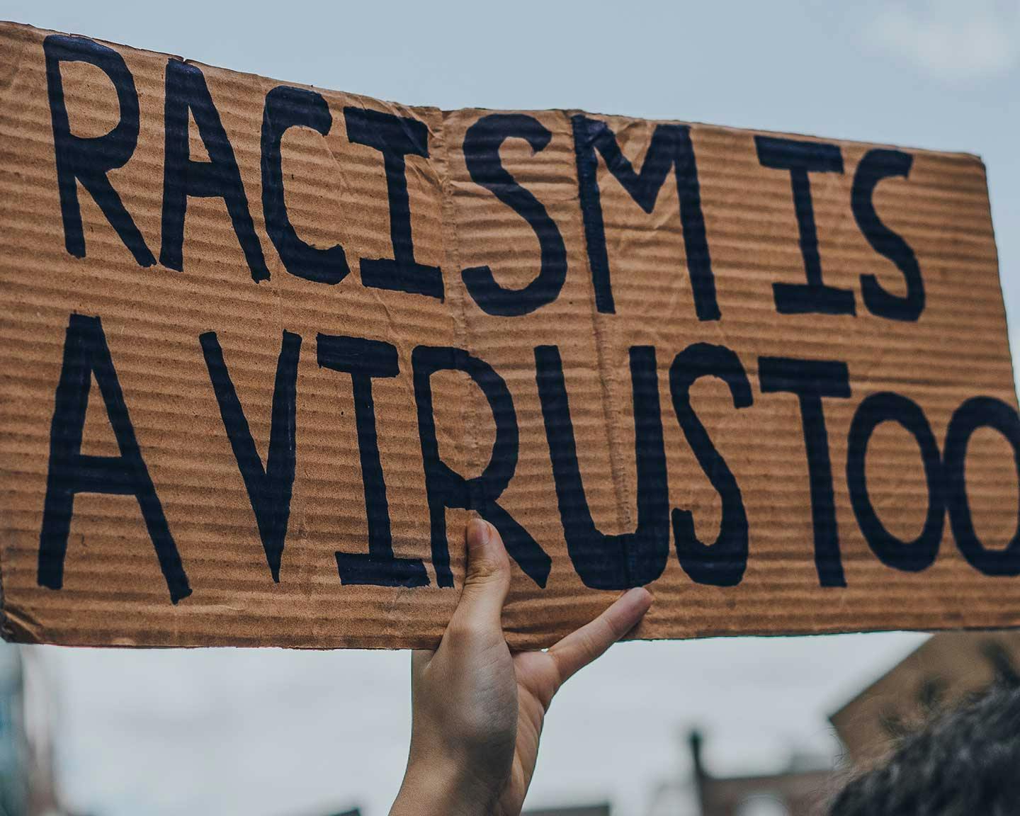 Protester holding a sign saying "Racism is a virus too"