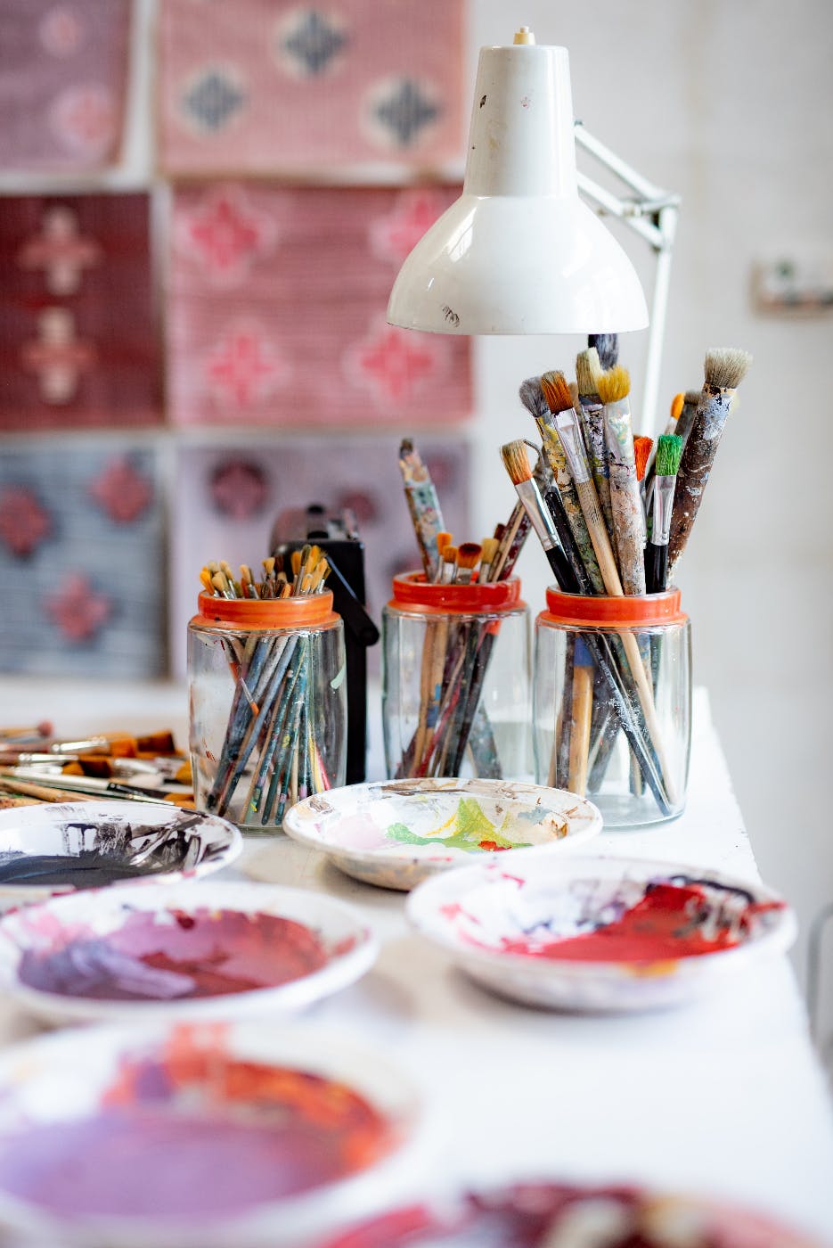 3 jars full of paint brushes, paper bowls full of paint