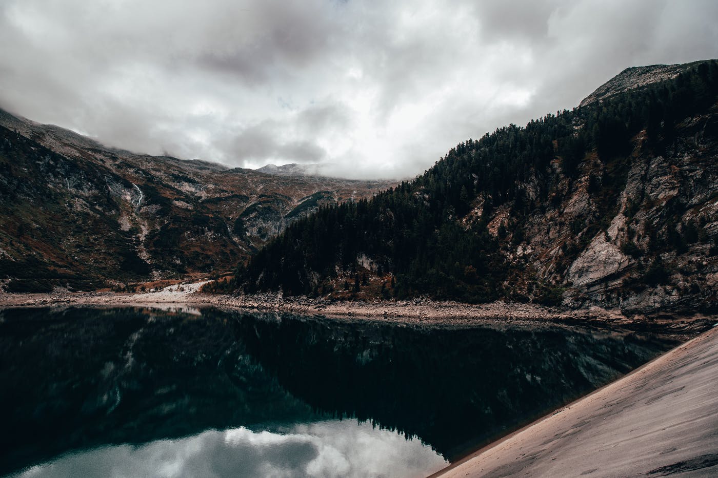 a lake surrounded by mountains under a leaden sky