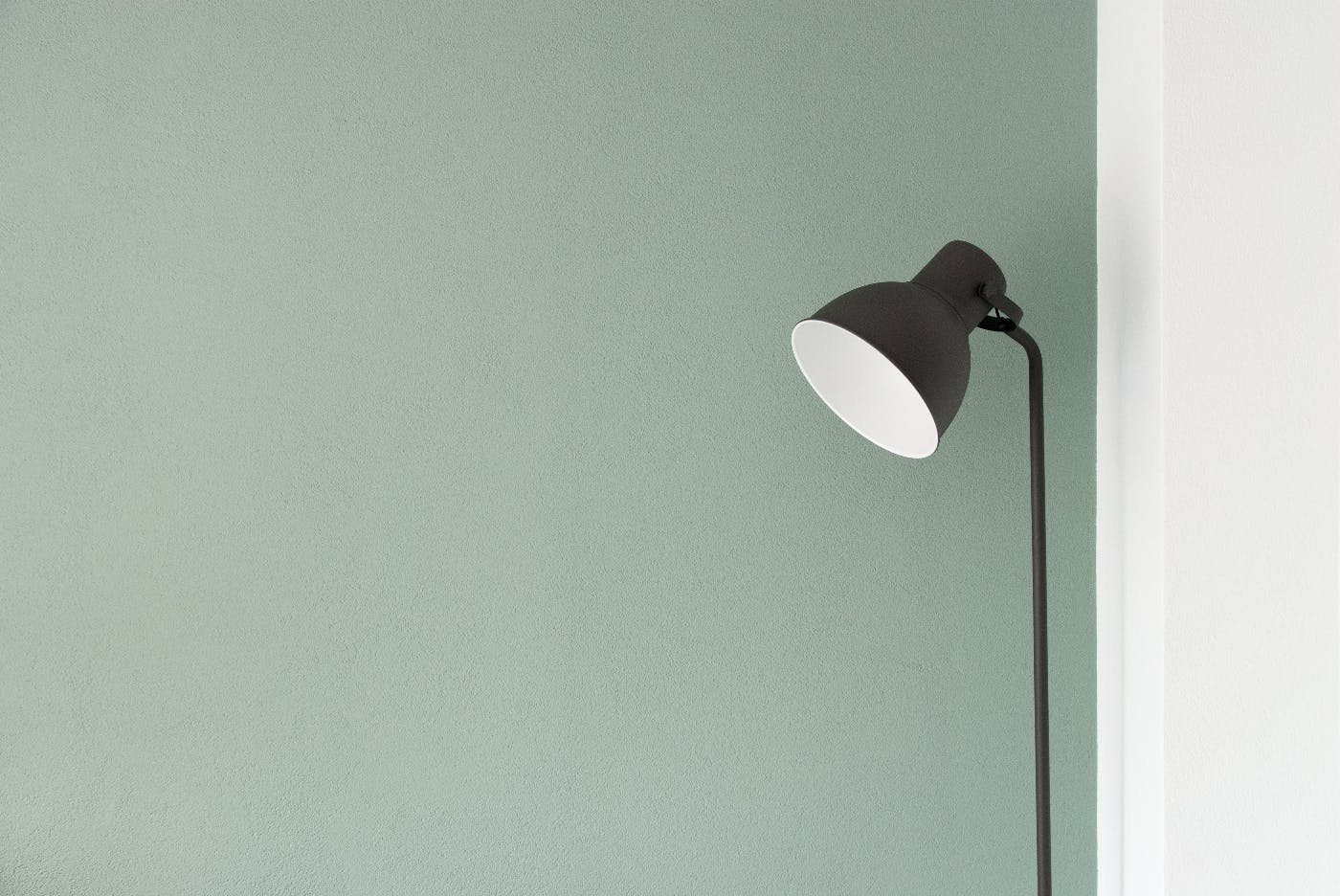 a black floor lamp against a green wall