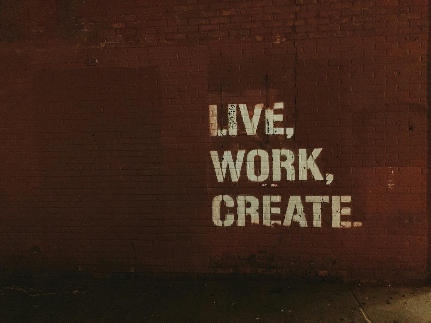 A brick wall with Live, Work, Create painted on it
