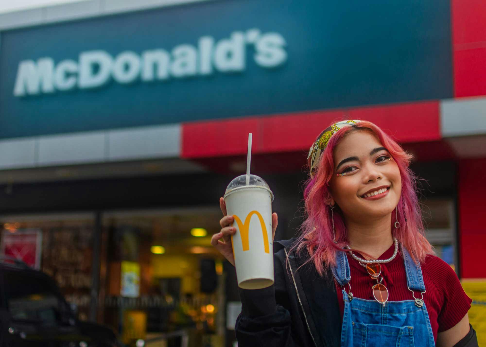 Girl enjoying a drink outside of a McDonald's