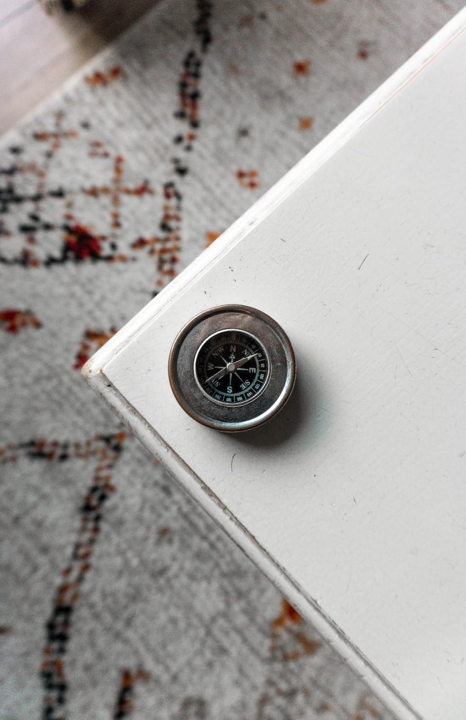 A tarnished silver compass on the edge of a white table