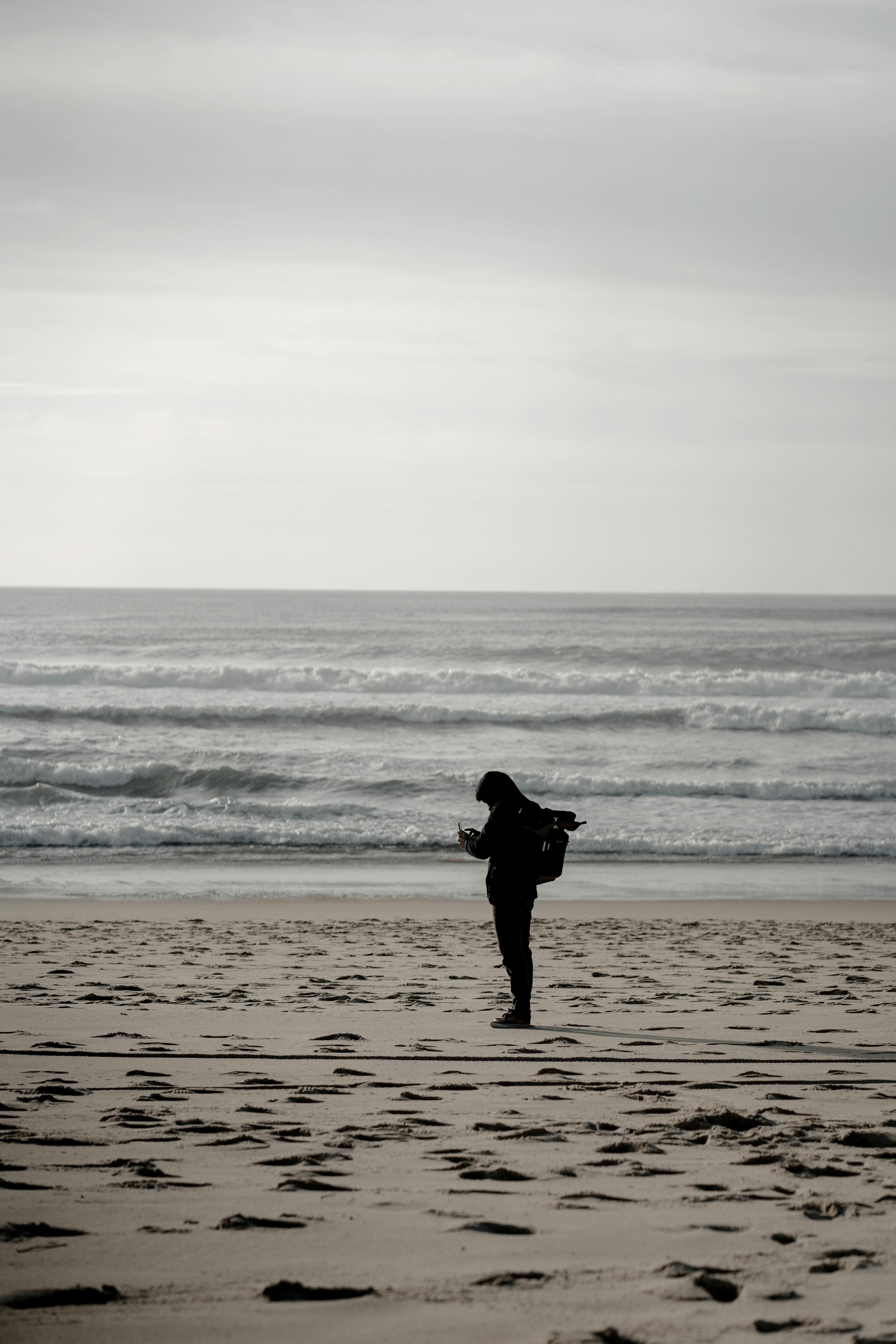 A person standing on a beach examining a chart