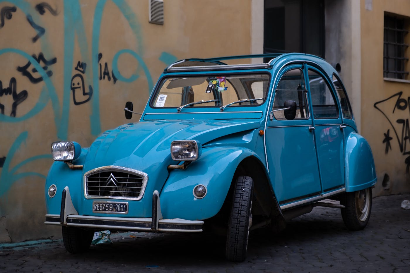 A blue car parked against a building