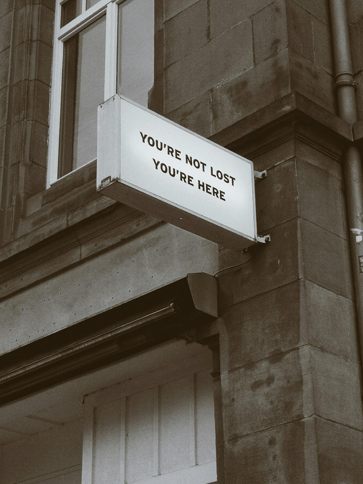 A sign on the side of a building reading: You're not lost, You're here.