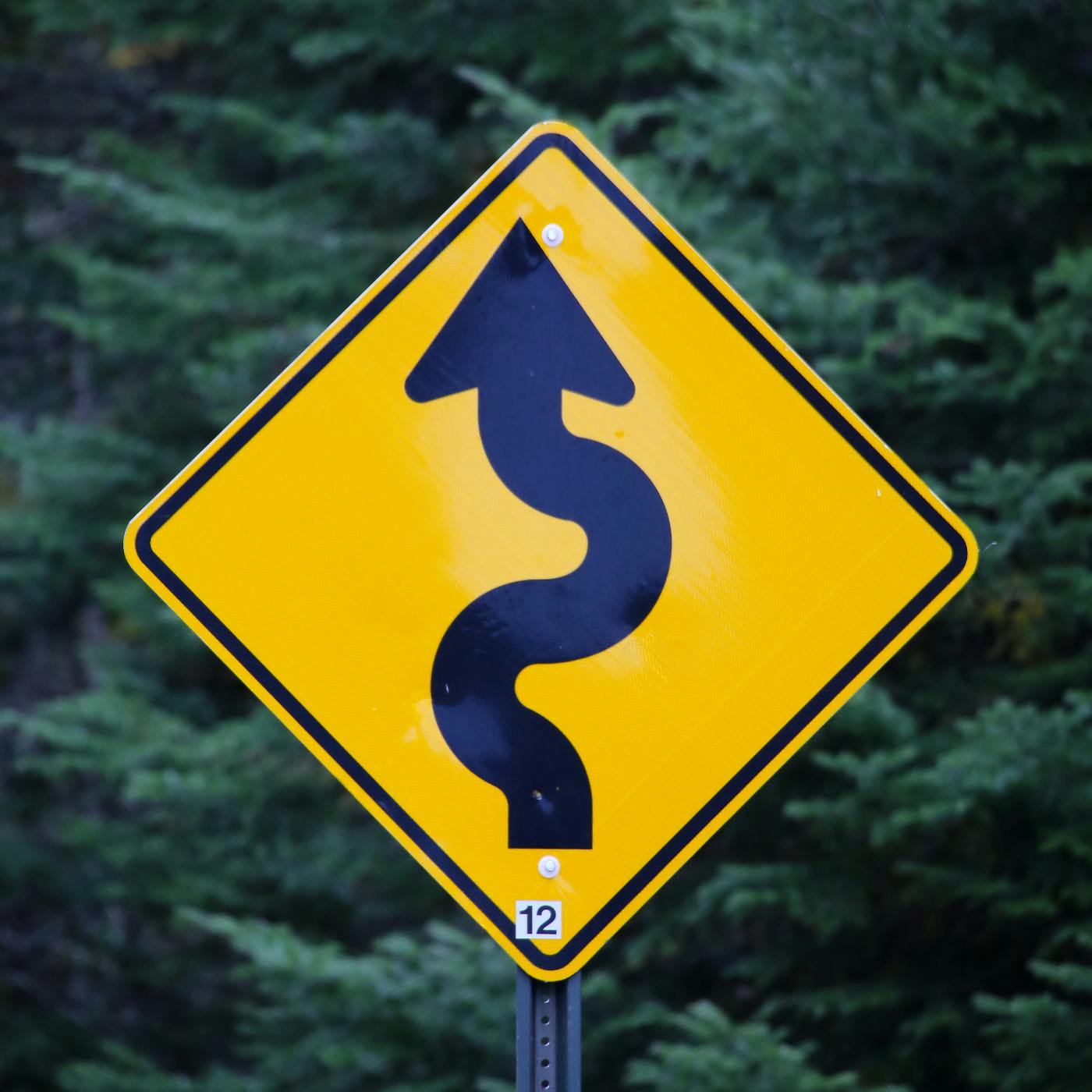 A yellow sign with a curvy arrow indicating a winding road