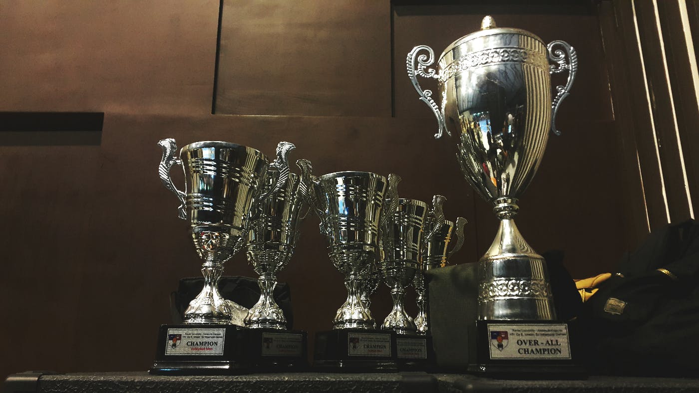 A shelf displaying one large and fiev smaller silver trophies