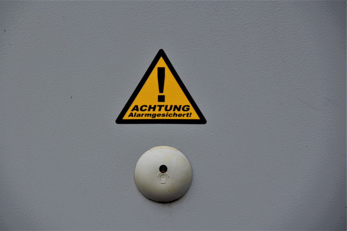 A triangular sign over a bell reading achtung!