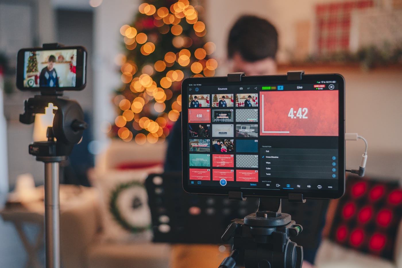 A smartphone on a tripod with a monitor and a Christmas scene