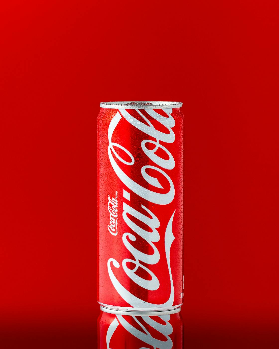 A slim can of Coca-Cola against a red background