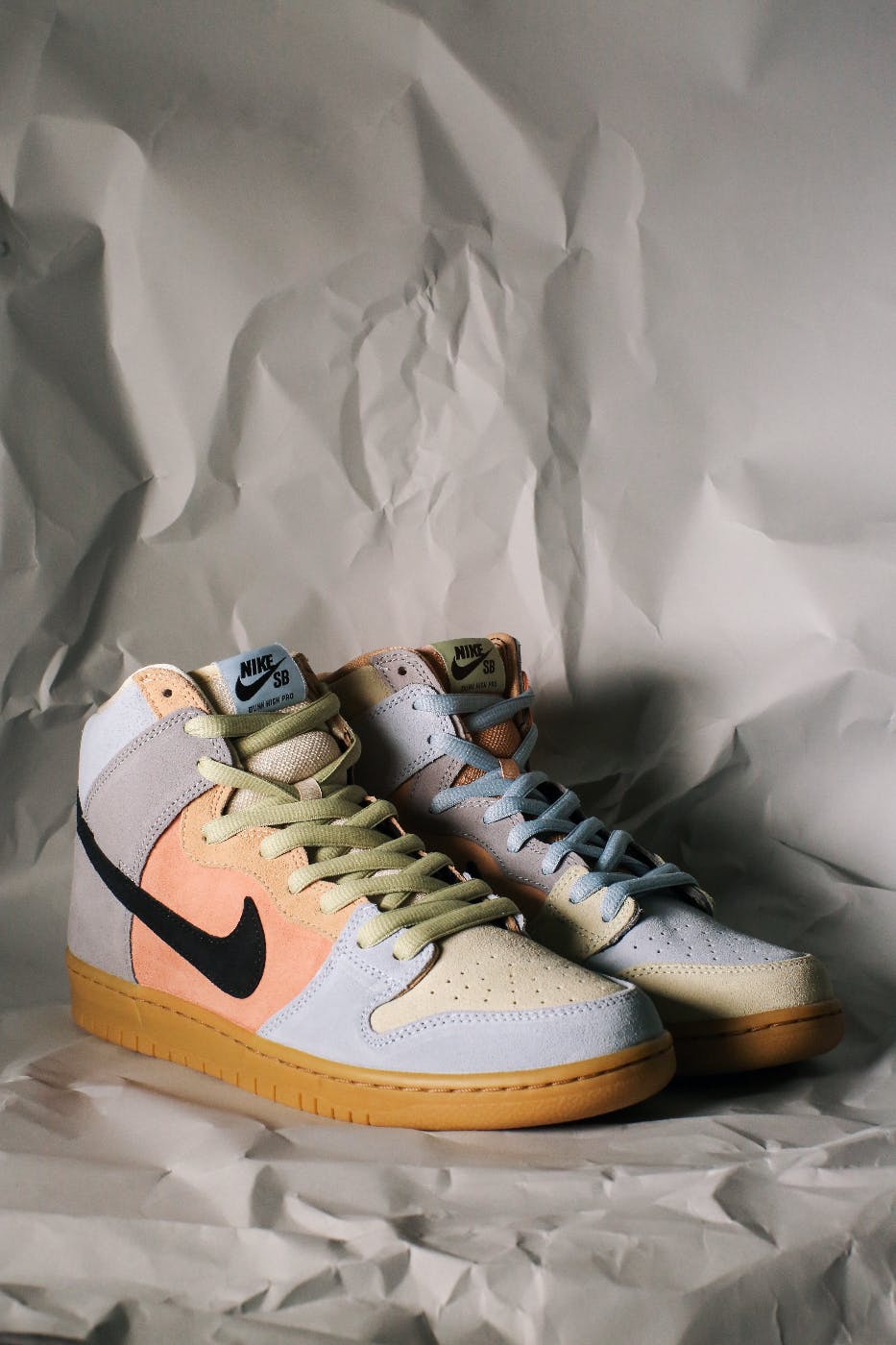 a pair of high top Nike sneakers in cream, grey and salmon with yellow laces and a black swoosh