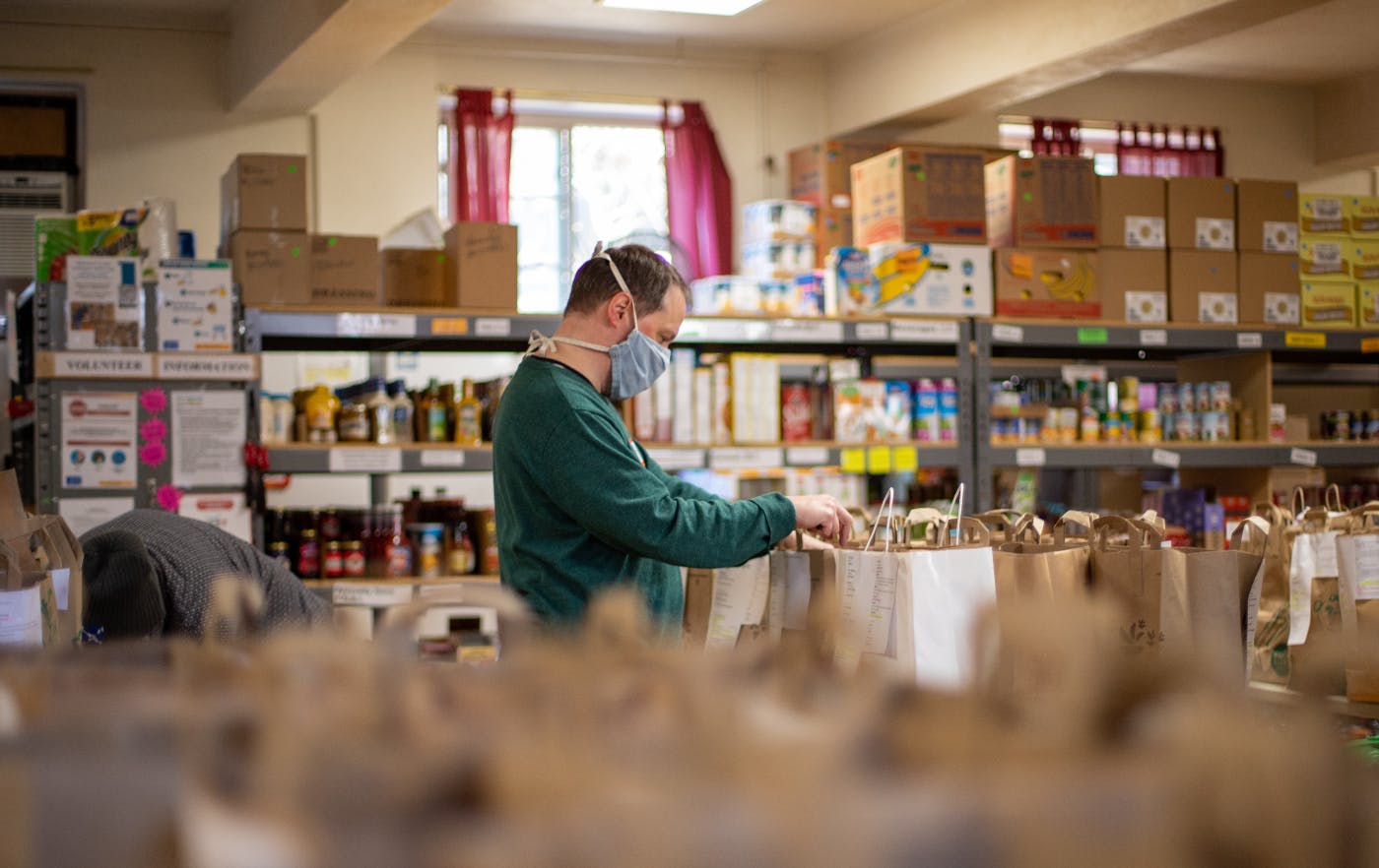 A man in  a green shirt putting food into donation bags