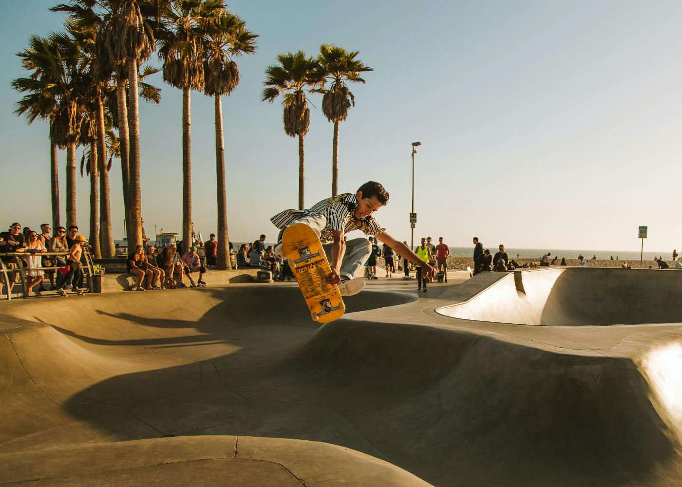 A boy in mid air on a skateboard in a seaside skate park