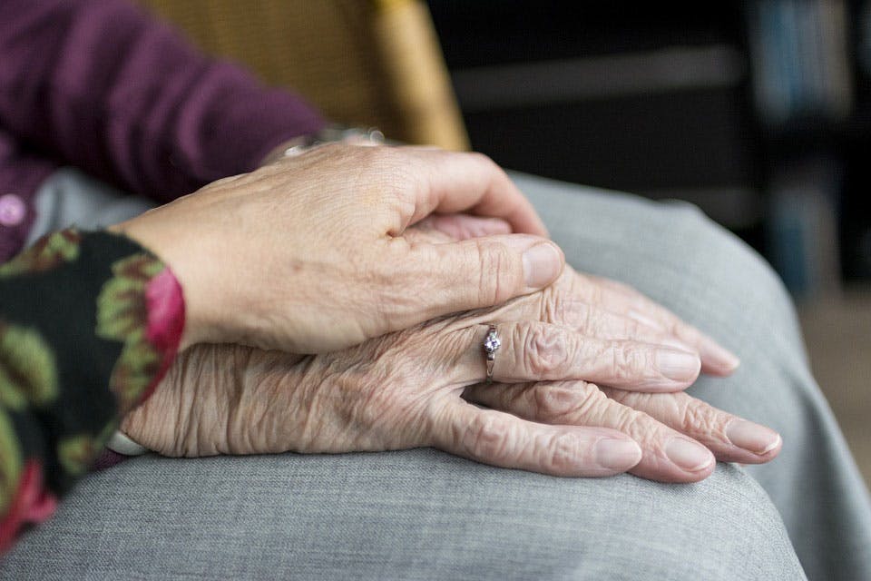 a close up of an elderly couple holding hands