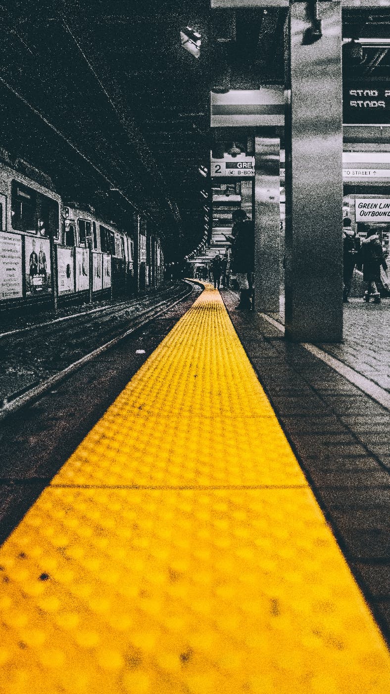 A New York subway platform in black and white with a yellow caution strip