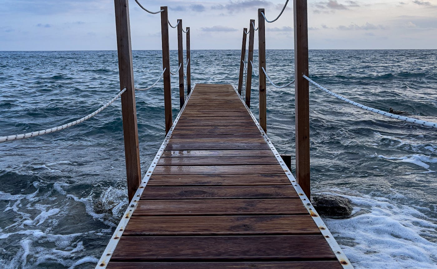 A wooden dock extending out into a very rough sea