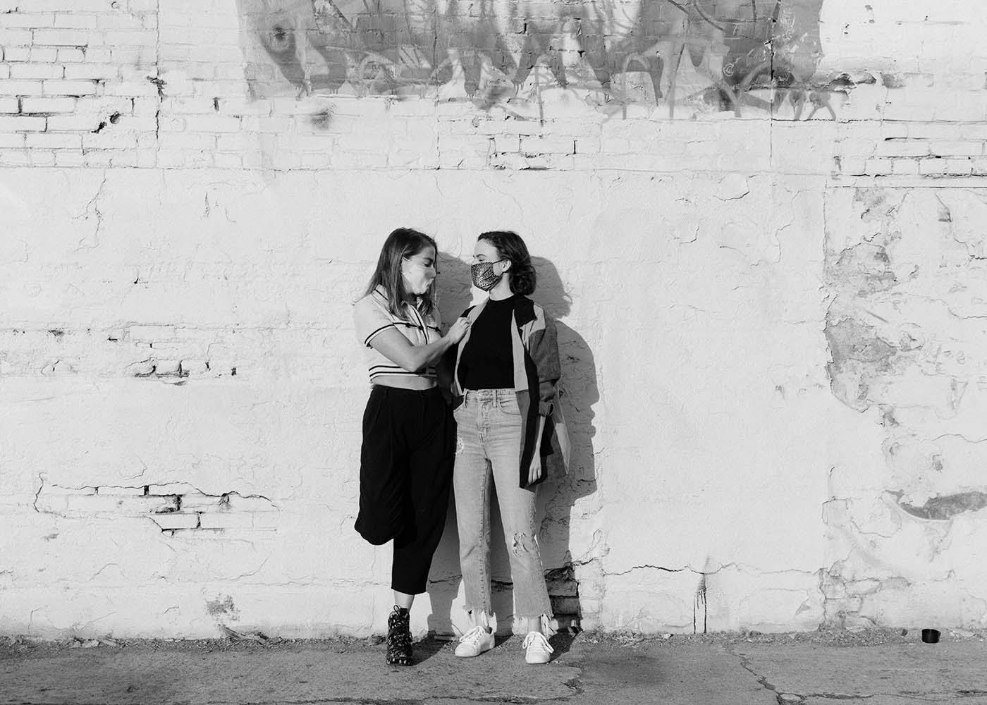 Two humans leaning against an old brick wall