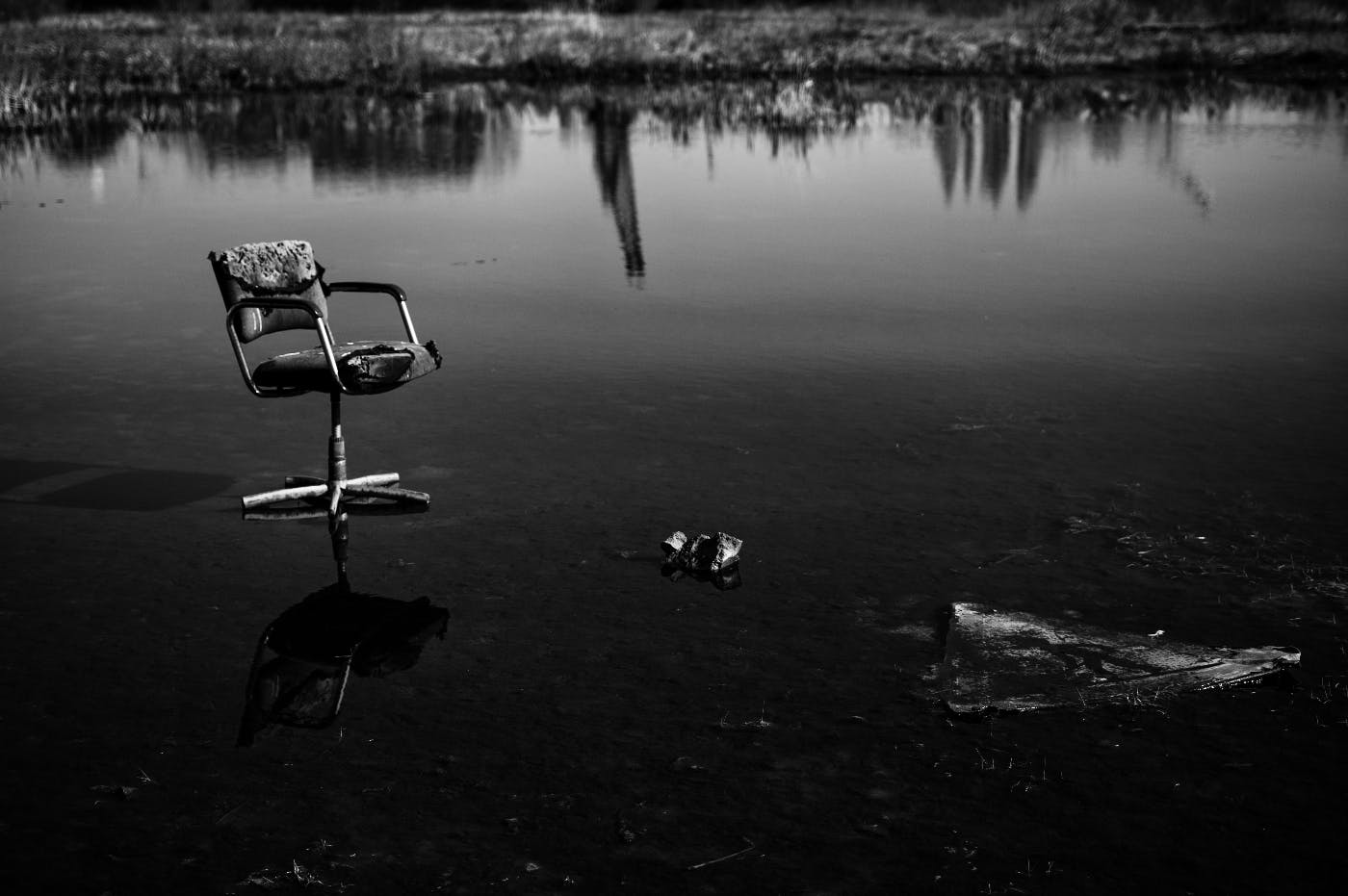 A black and white image of a decrepit swivel chair on a iced pond