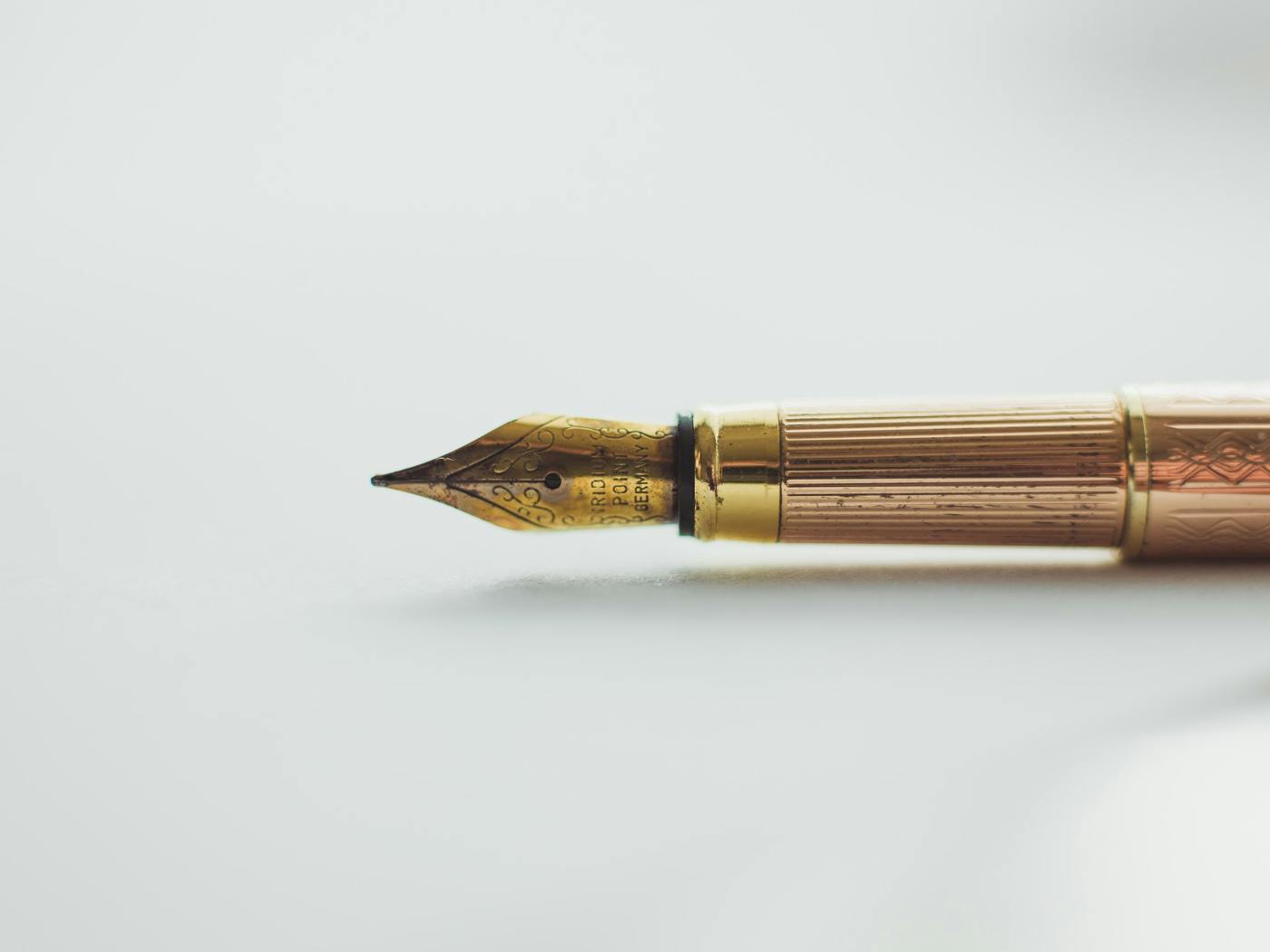 A fountain pen with a gold nib laying on its side