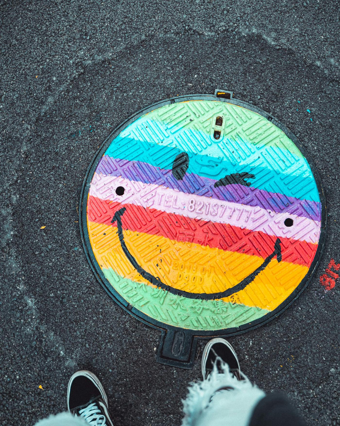 A manhole covered painted with a smiley face.