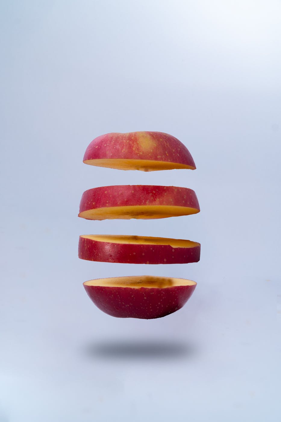 an apple cut into four slices floating in the air