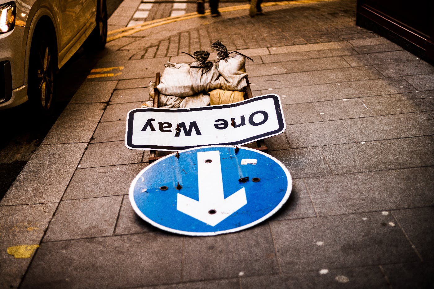 A one way sign laying on the sidewalk