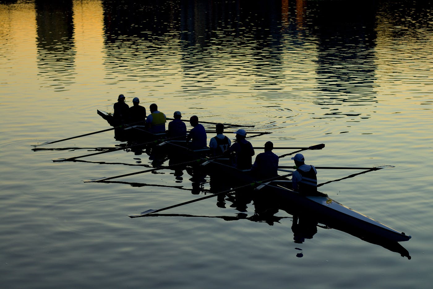 Nine men in a rowing shell at sunset