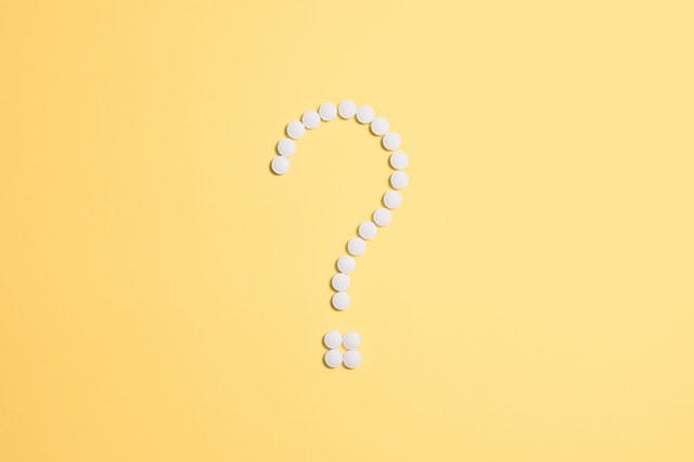 question mark made of pills on yellow background