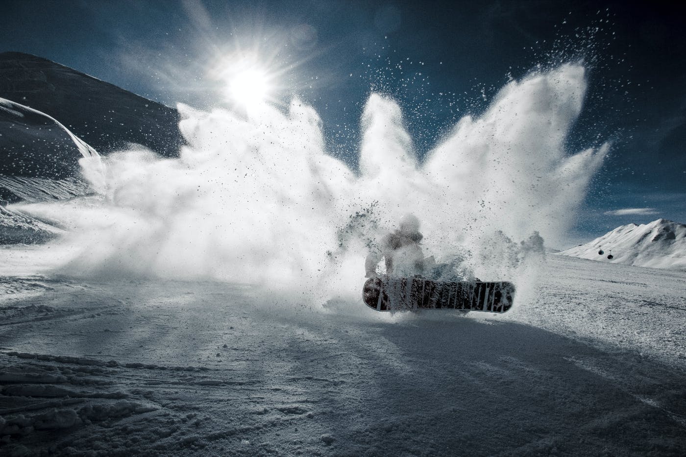 A snowboarder on a mountain kicking up a huge spray of snow