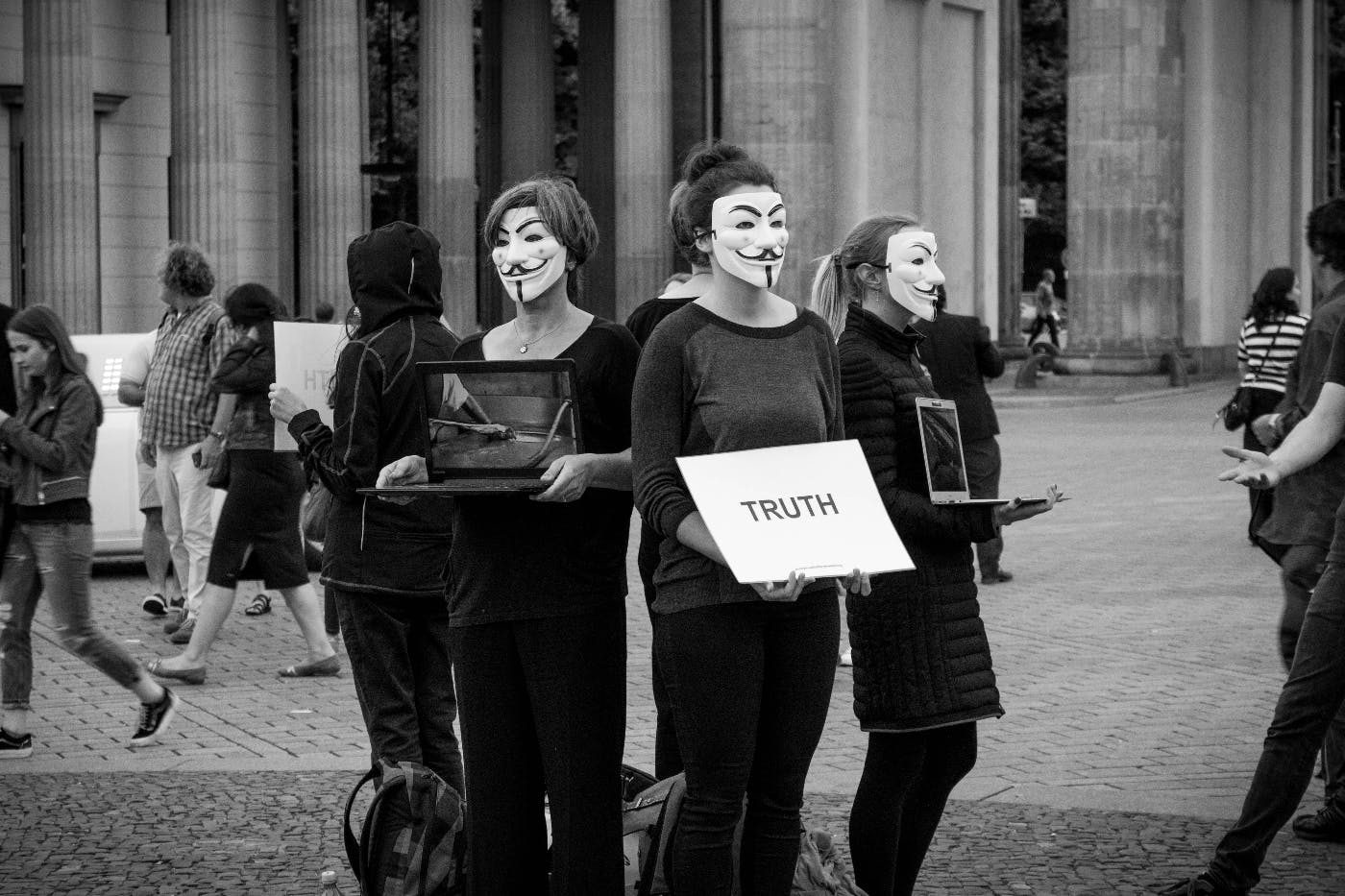 People in Vendetta masks holding a turth sign