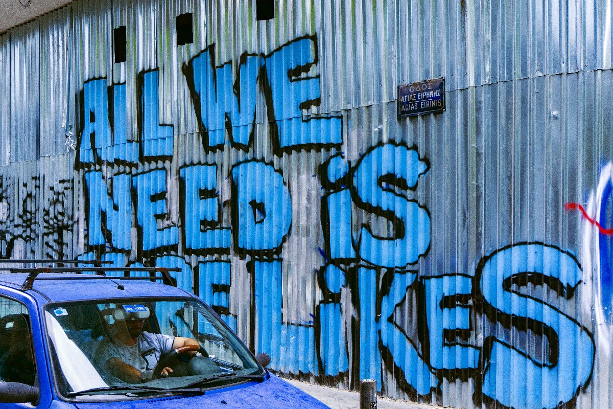 a steel wall with graffiti reading all we need is more likes