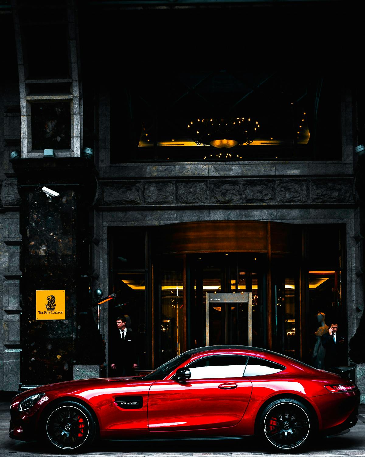 A red sports car in front of a luxury apartment building.