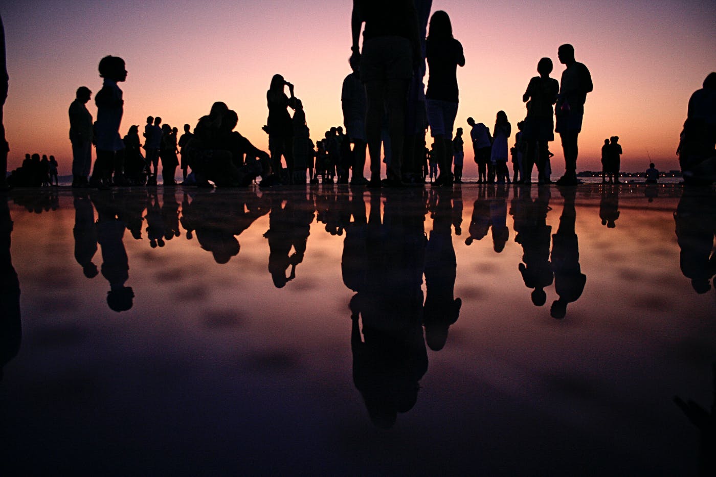 A group of people on wet sand their reflections in the wet sand