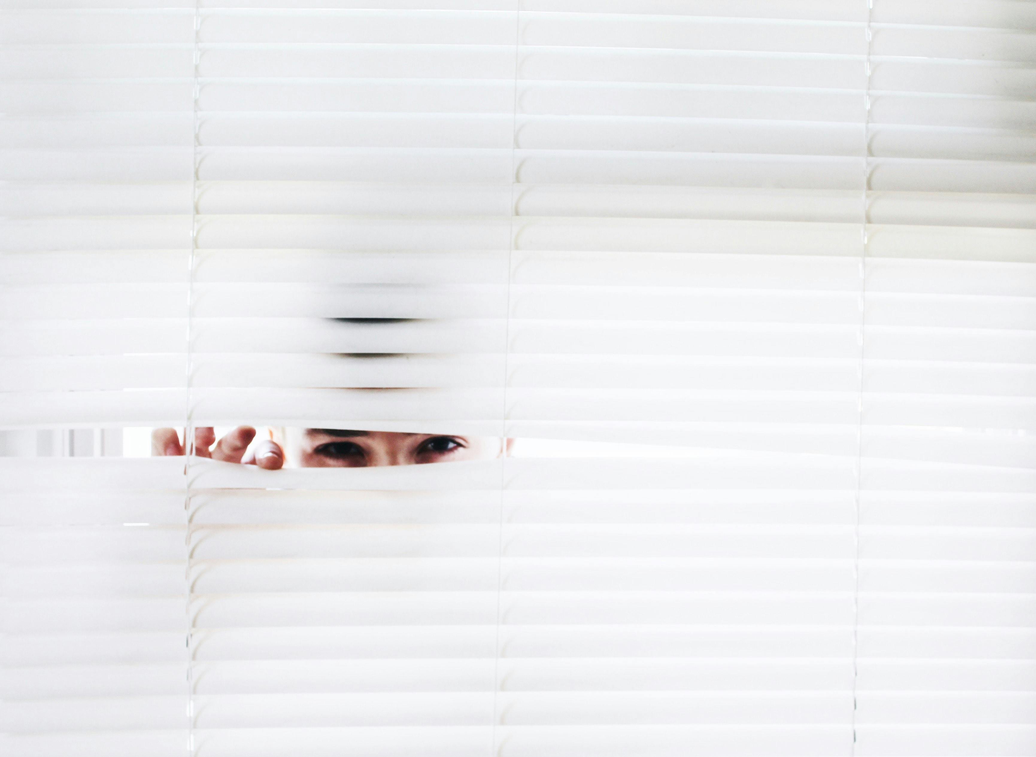 woman peeking out of blinds