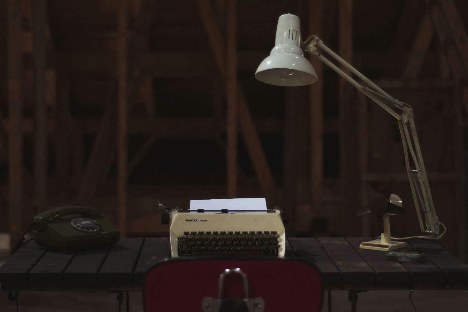 A desk appointed with a typewriter and lamp