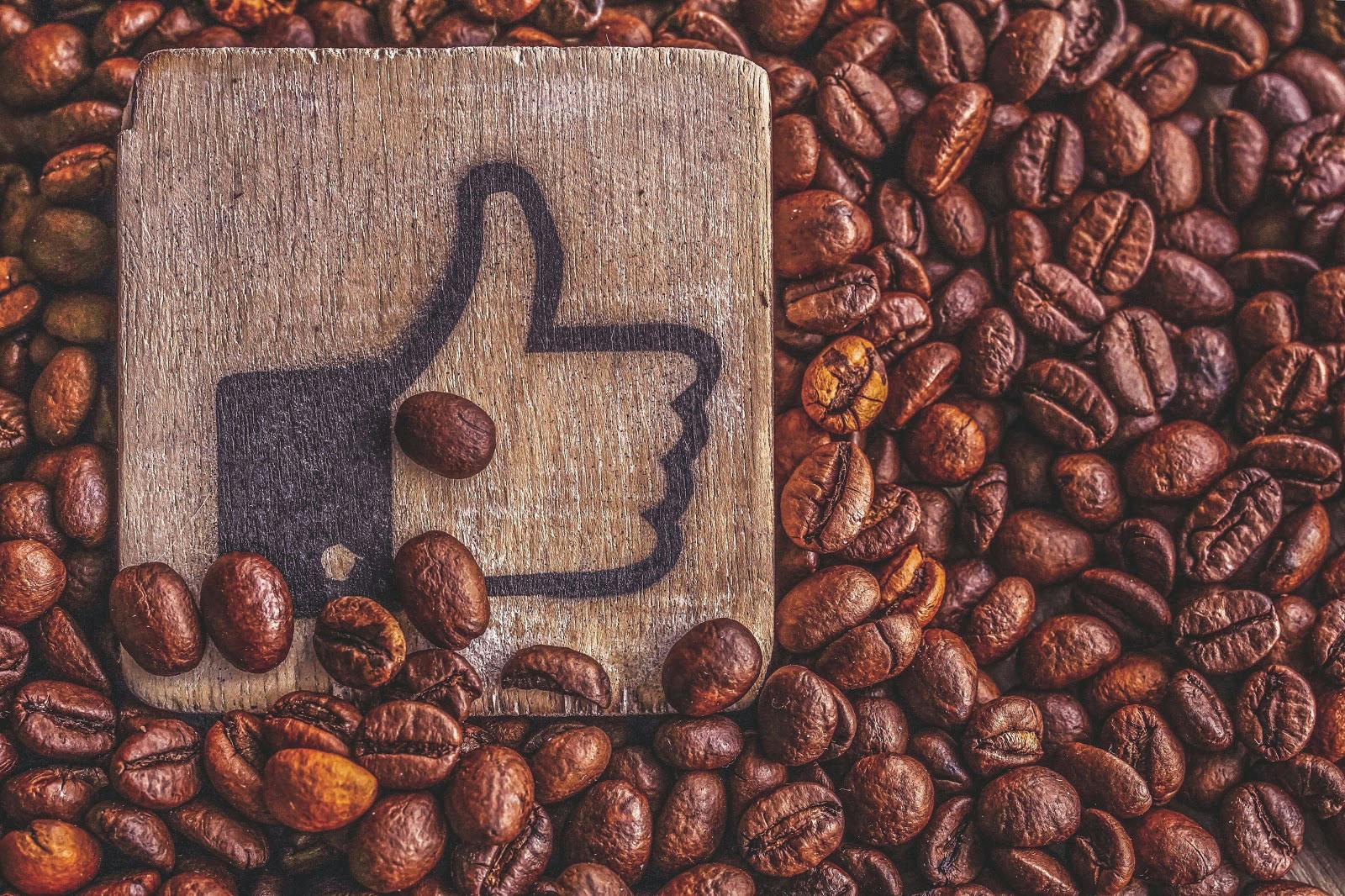 coffee beans with a wooden sign branded with the Facebook like emoticon