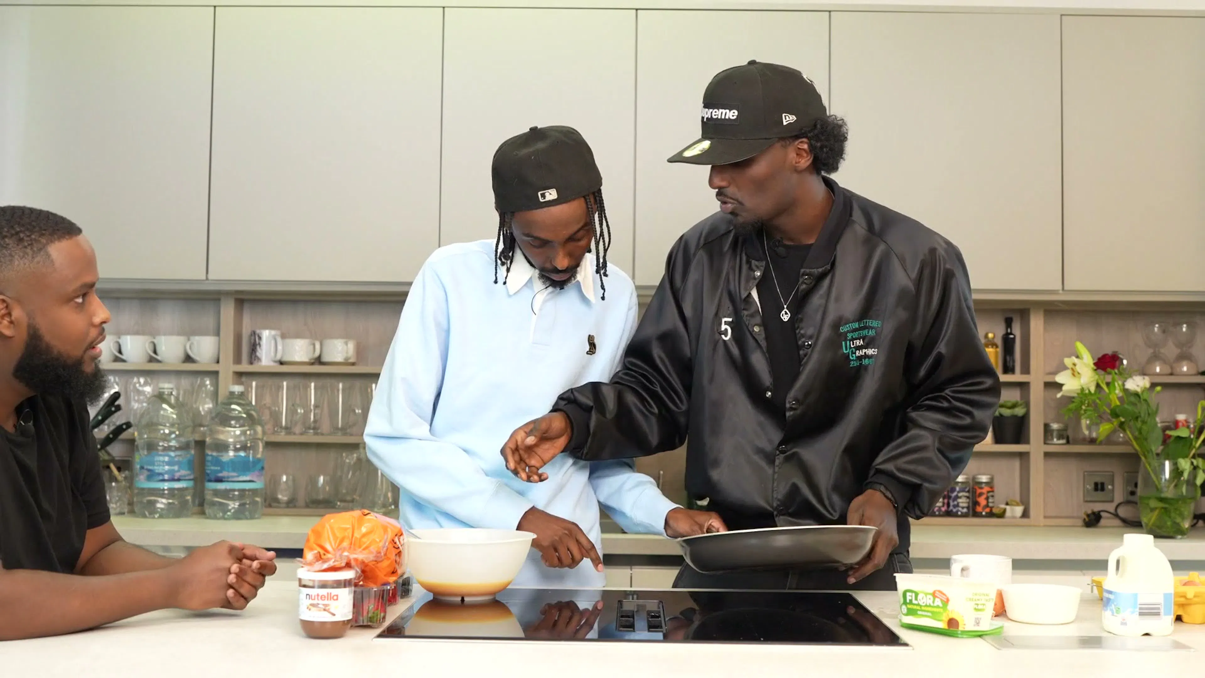 Two hosts talking behind the kitchen counter on the set of Behind The Stove